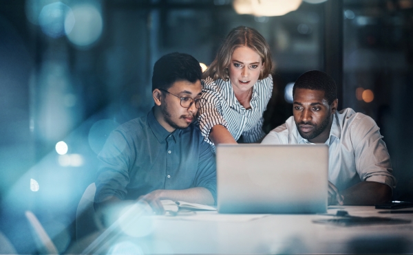 Group of business associates huddled by a laptop screen